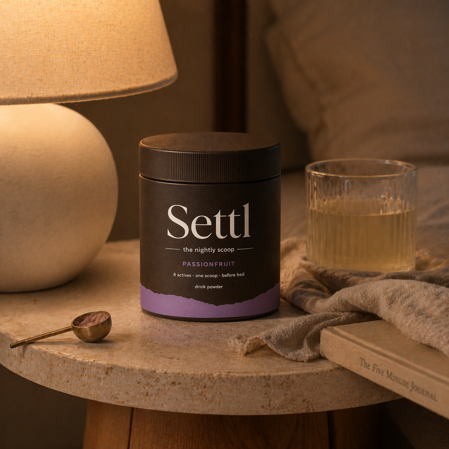 Settl tub and glass on a bedside table in warm lamp light.