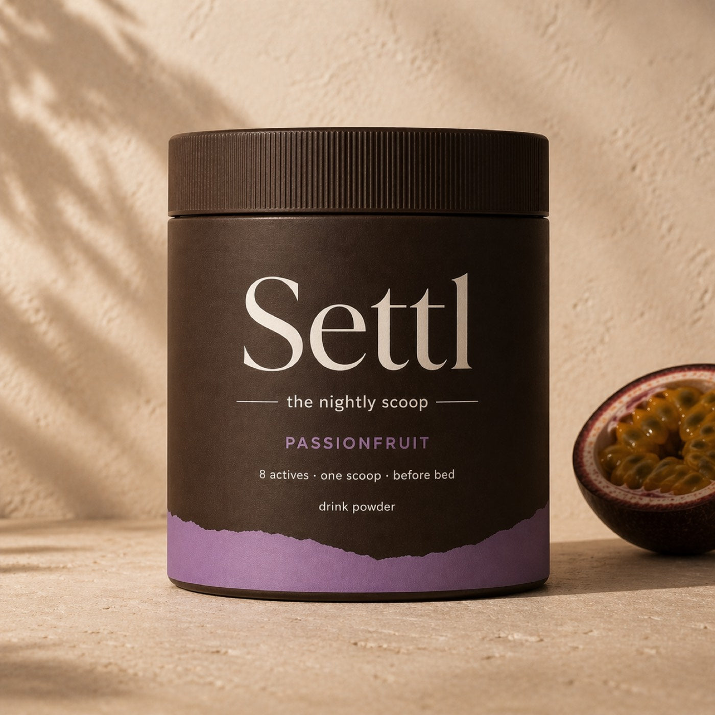 Settl Passionfruit tub of nightly drink powder beside a fresh passionfruit.
