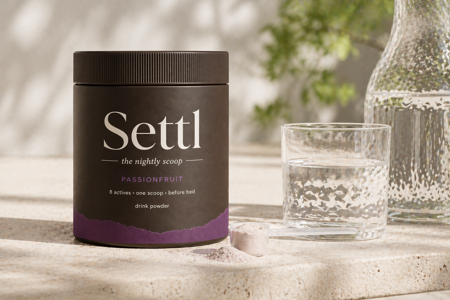 Settl tub and an empty glass on a travertine surface in morning light with soft plant shadows.